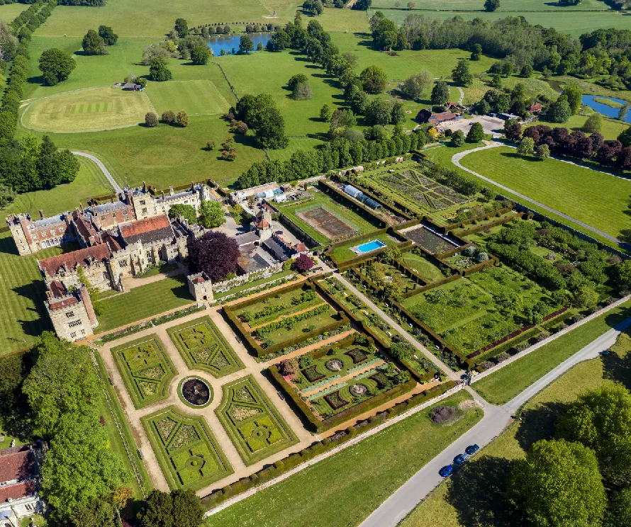 An aerial view of Penshurst Place, its walled formal gardens laid out in squares, and the parkland beyond.